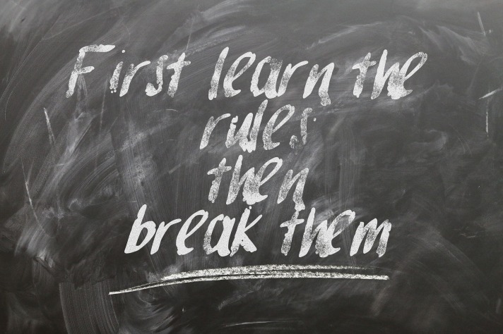 A chalk board with the phrase, learn the rules, then break them, indicating you must understand English grammar rules before you can break them.